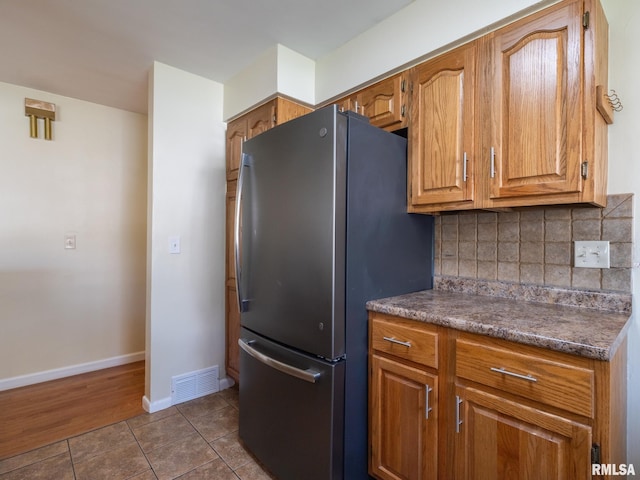 621 E Sciota Ave, Peoria Heights, IL 61616 - kitchen with freestanding refrigerator, dark countertops, dark tile patterned flooring, backsplash, and brown cabinets