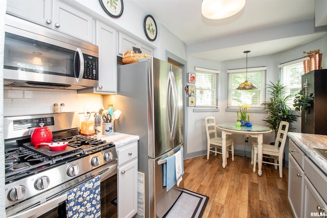 202 Esser St, Washington, IL 61571 - kitchen with stainless steel appliances, light wood-style flooring, tasteful backsplash, light countertops, and hanging light fixtures