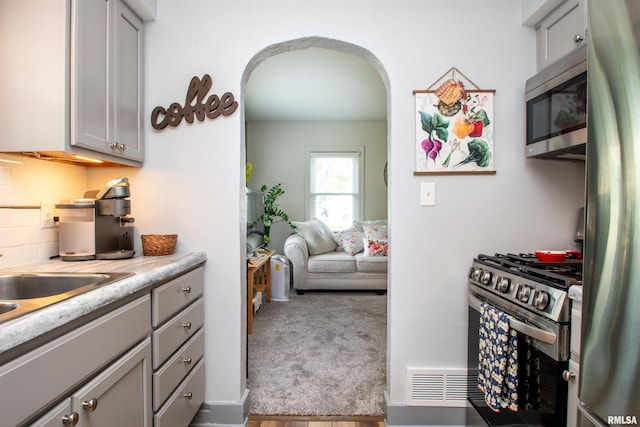 202 Esser St, Washington, IL 61571 - kitchen featuring stainless steel appliances, gray cabinets, arched walkways, light countertops, and decorative backsplash