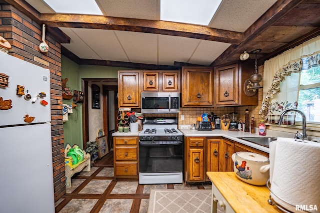 509 W Mcclure Ave, Peoria, IL 61604 - kitchen featuring white appliances, light countertops, brown cabinetry, and beam ceiling