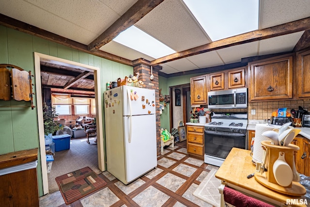509 W Mcclure Ave, Peoria, IL 61604 - kitchen with freestanding refrigerator, range with gas cooktop, stainless steel microwave, light countertops, and inlaid floor details