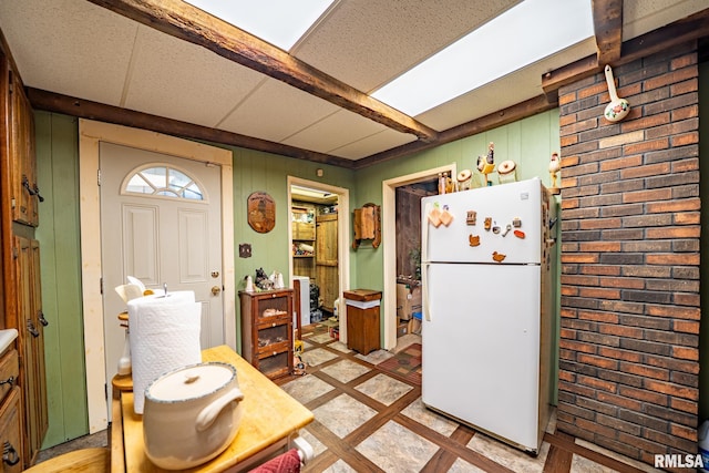 509 W Mcclure Ave, Peoria, IL 61604 - kitchen with freestanding refrigerator, inlaid floor details, brick wall, and wood walls