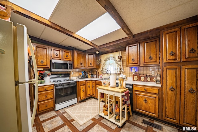 509 W Mcclure Ave, Peoria, IL 61604 - kitchen with white appliances, brown cabinetry, light countertops, and tasteful backsplash