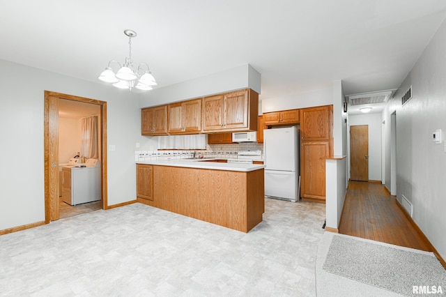 113 Highview Ter, East Peoria, IL 61611 - kitchen with white appliances, a peninsula, washer and clothes dryer, brown cabinetry, and a chandelier