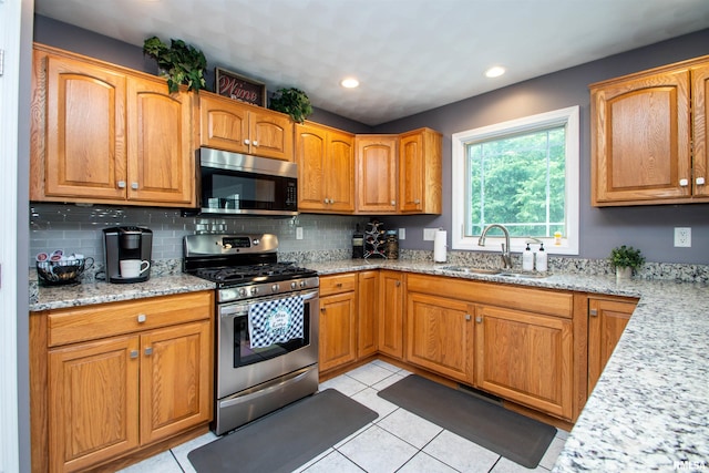 116 Field Ct, East Peoria, IL 61611 - kitchen with stainless steel appliances, light stone counters, tasteful backsplash, light tile patterned floors, and brown cabinetry