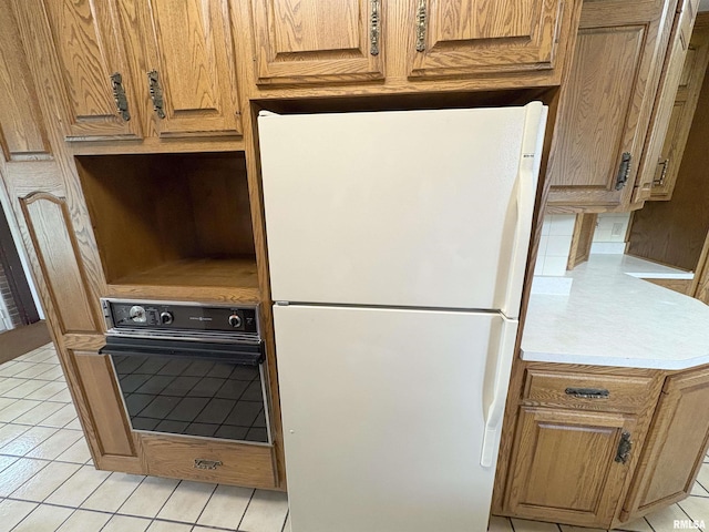 502 W Crestwood Dr, Peoria, IL 61614 - kitchen with freestanding refrigerator, black oven, light tile patterned floors, and light countertops
