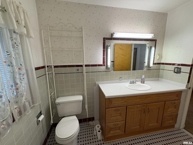 502 W Crestwood Dr, Peoria, IL 61614 - bathroom with tile walls, a wainscoted wall, vanity, wallpapered walls, and tile patterned flooring