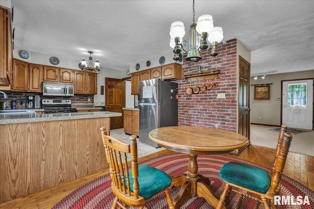 1522 N Stone School Rd, Elmwood, IL 61529 - kitchen featuring a chandelier, stainless steel appliances, brown cabinetry, backsplash, and light wood-style floors