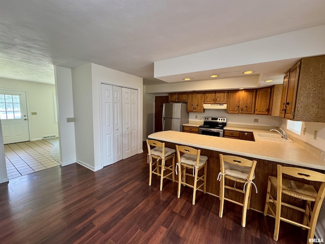 133 Holden Dr, Macomb, IL 61455 - kitchen featuring appliances with stainless steel finishes, brown cabinets, light countertops, a peninsula, and under cabinet range hood