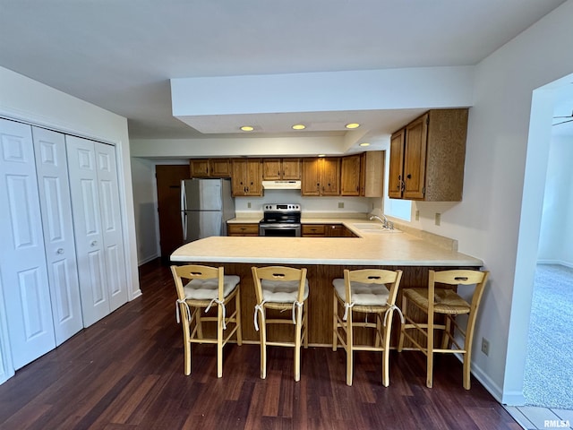 133 Holden Dr, Macomb, IL 61455 - kitchen with appliances with stainless steel finishes, under cabinet range hood, brown cabinetry, dark wood-style floors, and light countertops