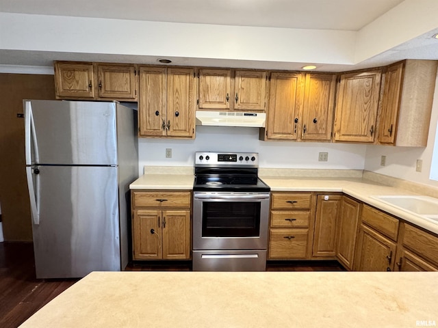 133 Holden Dr, Macomb, IL 61455 - kitchen featuring appliances with stainless steel finishes, under cabinet range hood, light countertops, dark wood-style flooring, and brown cabinetry