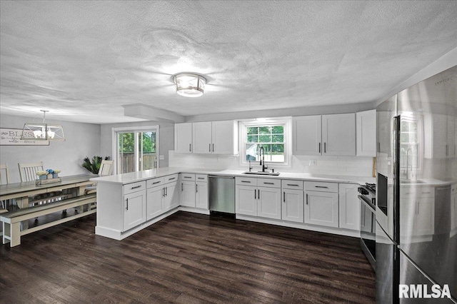 1536 Hickory Point Rd, Metamora, IL 61548 - kitchen featuring appliances with stainless steel finishes, a peninsula, white cabinetry, decorative backsplash, and a textured ceiling