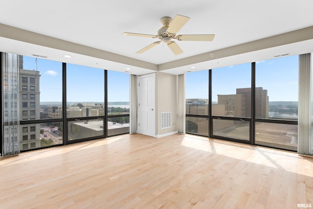 123 SW Jefferson St Unit E10C, Peoria, IL 61602 - spare room featuring floor to ceiling windows, wood finished floors, a city view, and a ceiling fan