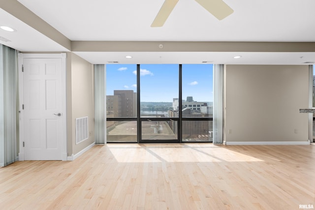 123 SW Jefferson St Unit E10C, Peoria, IL 61602 - spare room featuring wood finished floors, a view of city, ceiling fan, a wall of windows, and recessed lighting