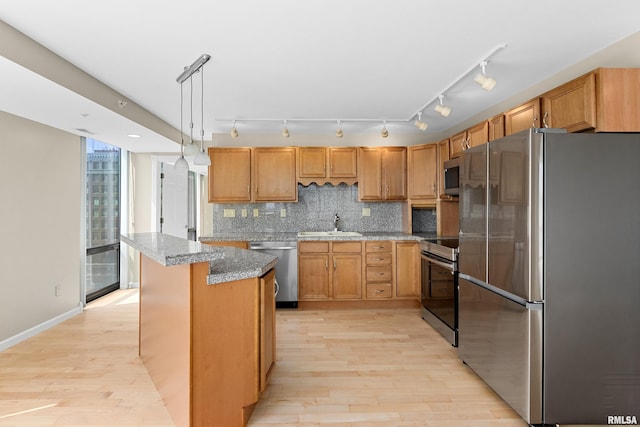 123 SW Jefferson St Unit E10C, Peoria, IL 61602 - kitchen featuring stainless steel appliances, tasteful backsplash, light wood-type flooring, a kitchen island, and hanging light fixtures