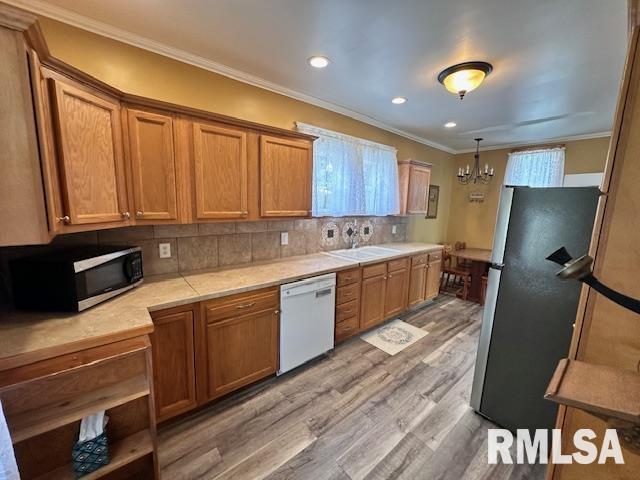964 E Locust St, Canton, IL 61520 - kitchen featuring appliances with stainless steel finishes, light wood-type flooring, light countertops, ornamental molding, and a chandelier