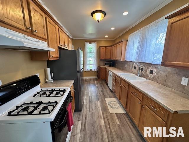 964 E Locust St, Canton, IL 61520 - kitchen with white appliances, under cabinet range hood, ornamental molding, wood finished floors, and brown cabinetry