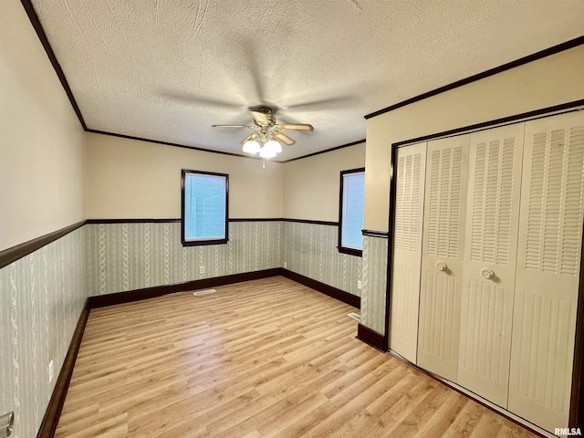 904 E Forrest Hill Ave, Peoria, IL 61603 - unfurnished bedroom featuring light wood-style floors, crown molding, wainscoting, ceiling fan, and a textured ceiling