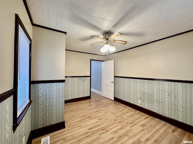 904 E Forrest Hill Ave, Peoria, IL 61603 - empty room with wood finished floors, a wainscoted wall, ceiling fan, crown molding, and a textured ceiling