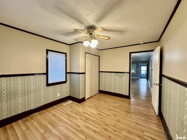 904 E Forrest Hill Ave, Peoria, IL 61603 - unfurnished bedroom with light wood-type flooring, wainscoting, crown molding, a textured ceiling, and a closet