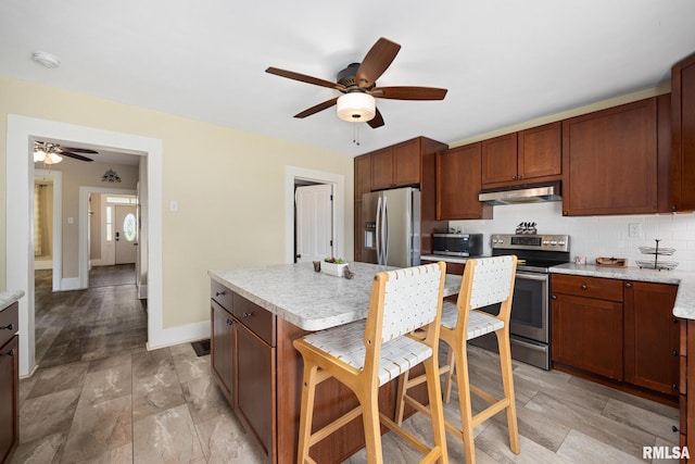 411 E 3rd St, Delavan, IL 61550 - kitchen with appliances with stainless steel finishes, under cabinet range hood, a ceiling fan, and a kitchen bar