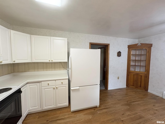 505 S Davenport St, Metamora, IL 61548 - kitchen with freestanding refrigerator, electric range, wood finished floors, white cabinets, and wallpapered walls