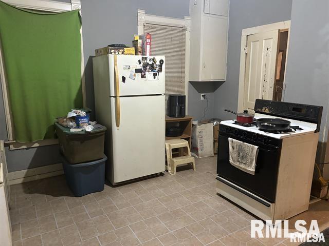 1608 S Lydia Ave, Peoria, IL 61605 - kitchen featuring gas stove, freestanding refrigerator, white cabinets, and light tile patterned floors