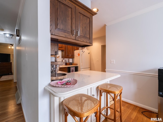 2705 N Victoria Ave, Peoria, IL 61604 - kitchen with freestanding refrigerator, ornamental molding, light wood-style floors, a kitchen bar, and light countertops