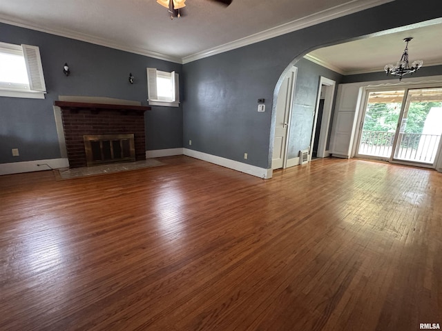 1210 W Macqueen Ave, Peoria, IL 61604 - unfurnished living room featuring arched walkways, healthy amount of natural light, a chandelier, wood finished floors, and crown molding