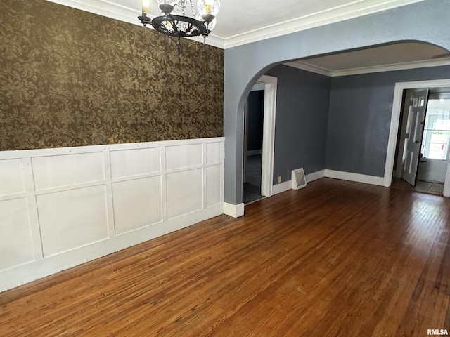 1210 W Macqueen Ave, Peoria, IL 61604 - unfurnished dining area with arched walkways, a chandelier, dark wood-style flooring, a wainscoted wall, and crown molding