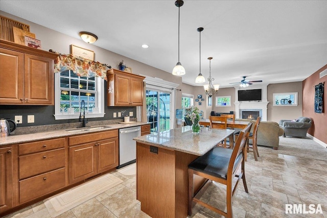 1712 Rustic Oak Dr, Washington, IL 61571 - kitchen with dishwasher, ceiling fan, brown cabinets, a warm lit fireplace, and a kitchen island