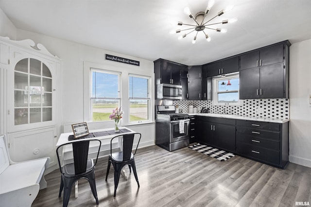1900 S Airport Rd, Peoria, IL 61607 - kitchen with stainless steel appliances, dark cabinetry, a chandelier, and healthy amount of natural light