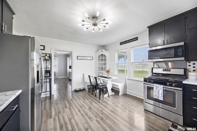 1900 S Airport Rd, Peoria, IL 61607 - kitchen featuring appliances with stainless steel finishes, a chandelier, dark cabinetry, and light wood-style flooring