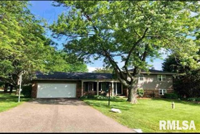 8109 N Blackbridge Rd, Edwards, IL 61528 - tri-level home with asphalt driveway, a front lawn, and an attached garage