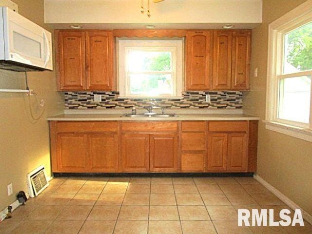 320 E Meadow Lawn St, Manito, IL 61546 - kitchen featuring white microwave, light countertops, decorative backsplash, and brown cabinets