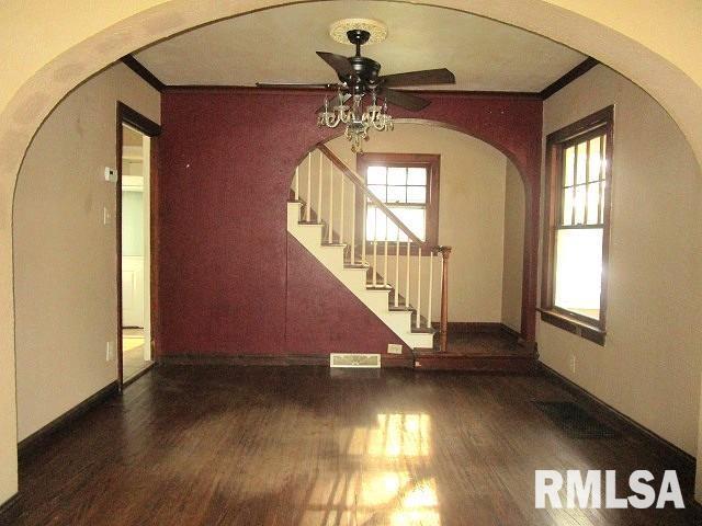 320 E Meadow Lawn St, Manito, IL 61546 - unfurnished living room featuring ceiling fan, wood finished floors, ornamental molding, stairs, and arched walkways