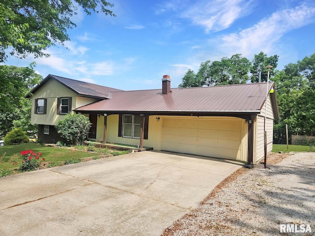 1003 Tonti Rd, Toulon, IL 61483 - split level home featuring an attached garage, a metal roof, driveway, a chimney, and a front yard