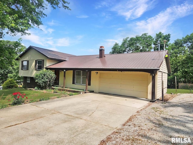 1003 Tonti Rd, Toulon, IL 61483 - tri-level home with a garage, a metal roof, driveway, a chimney, and a front lawn