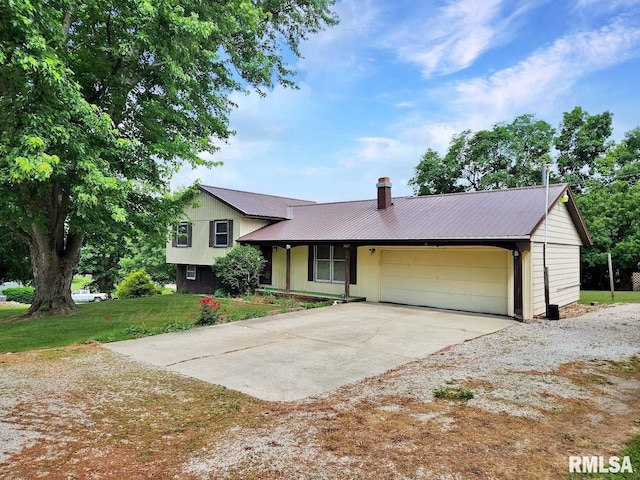 1003 Tonti Rd, Toulon, IL 61483 - split level home with a garage, driveway, a metal roof, a chimney, and a front yard