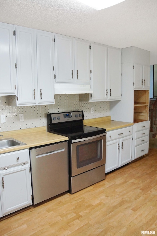 1003 Tonti Rd, Toulon, IL 61483 - kitchen featuring appliances with stainless steel finishes, under cabinet range hood, white cabinets, light wood-style floors, and light countertops