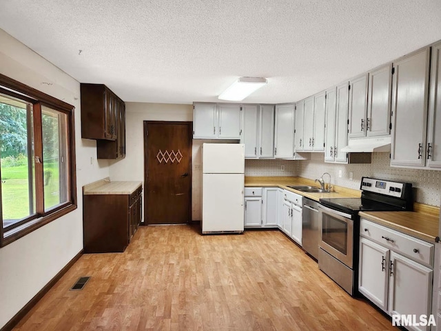1003 Tonti Rd, Toulon, IL 61483 - kitchen with stainless steel appliances, under cabinet range hood, light wood-style floors, and a textured ceiling