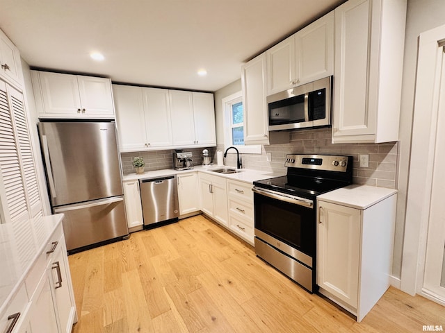 702 S Pearl St, Macomb, IL 61455 - kitchen with stainless steel appliances, tasteful backsplash, light countertops, light wood finished floors, and white cabinets