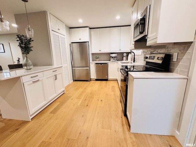 702 S Pearl St, Macomb, IL 61455 - kitchen with stainless steel appliances, light wood-style floors, white cabinetry, a peninsula, and backsplash