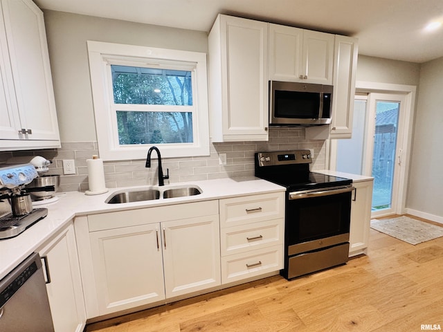 702 S Pearl St, Macomb, IL 61455 - kitchen with appliances with stainless steel finishes, light wood-style floors, decorative backsplash, and white cabinetry