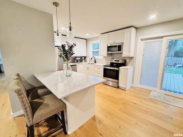 702 S Pearl St, Macomb, IL 61455 - kitchen with stainless steel appliances, backsplash, light wood-style floors, a breakfast bar area, and a peninsula