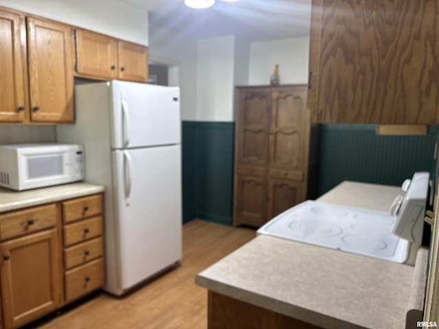 626 N Main St, Lewistown, IL 61542 - kitchen with white appliances, light wood-style floors, light countertops, and brown cabinetry