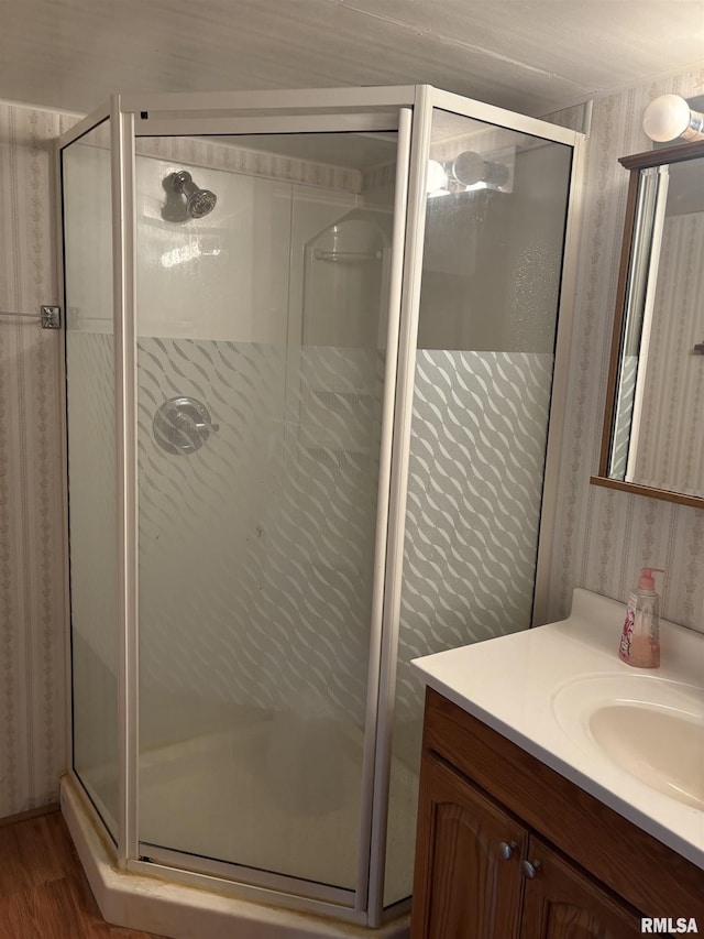 626 N Main St, Lewistown, IL 61542 - bathroom featuring vanity, a stall shower, wood finished floors, and wallpapered walls