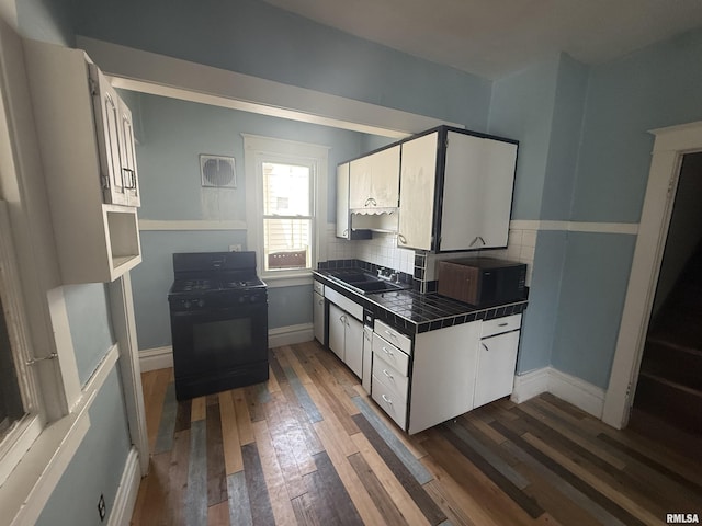 1712 W Bradley Ave, Peoria, IL 61606 - kitchen featuring tile counters, black appliances, dark wood-style flooring, decorative backsplash, and white cabinetry