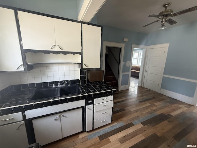1712 W Bradley Ave, Peoria, IL 61606 - kitchen with tile countertops, white cabinetry, decorative backsplash, a ceiling fan, and wood finished floors