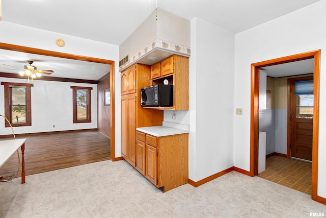 16905 E 1600th St, Bushnell, IL 61422 - kitchen featuring black microwave, a ceiling fan, light countertops, open floor plan, and brown cabinetry